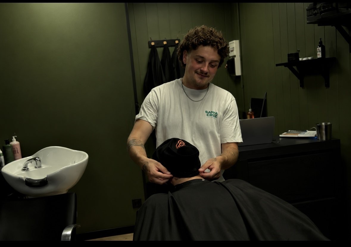 Le barbier ajuste une serviette autour du cou d'un client dans le salon aux murs kaki