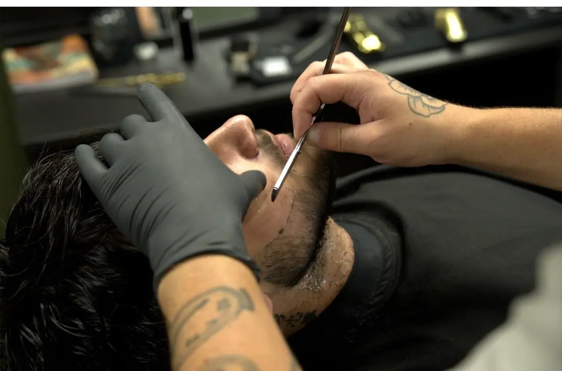 Taille de barbe au pinceau, gros plan sur le geste du barbier